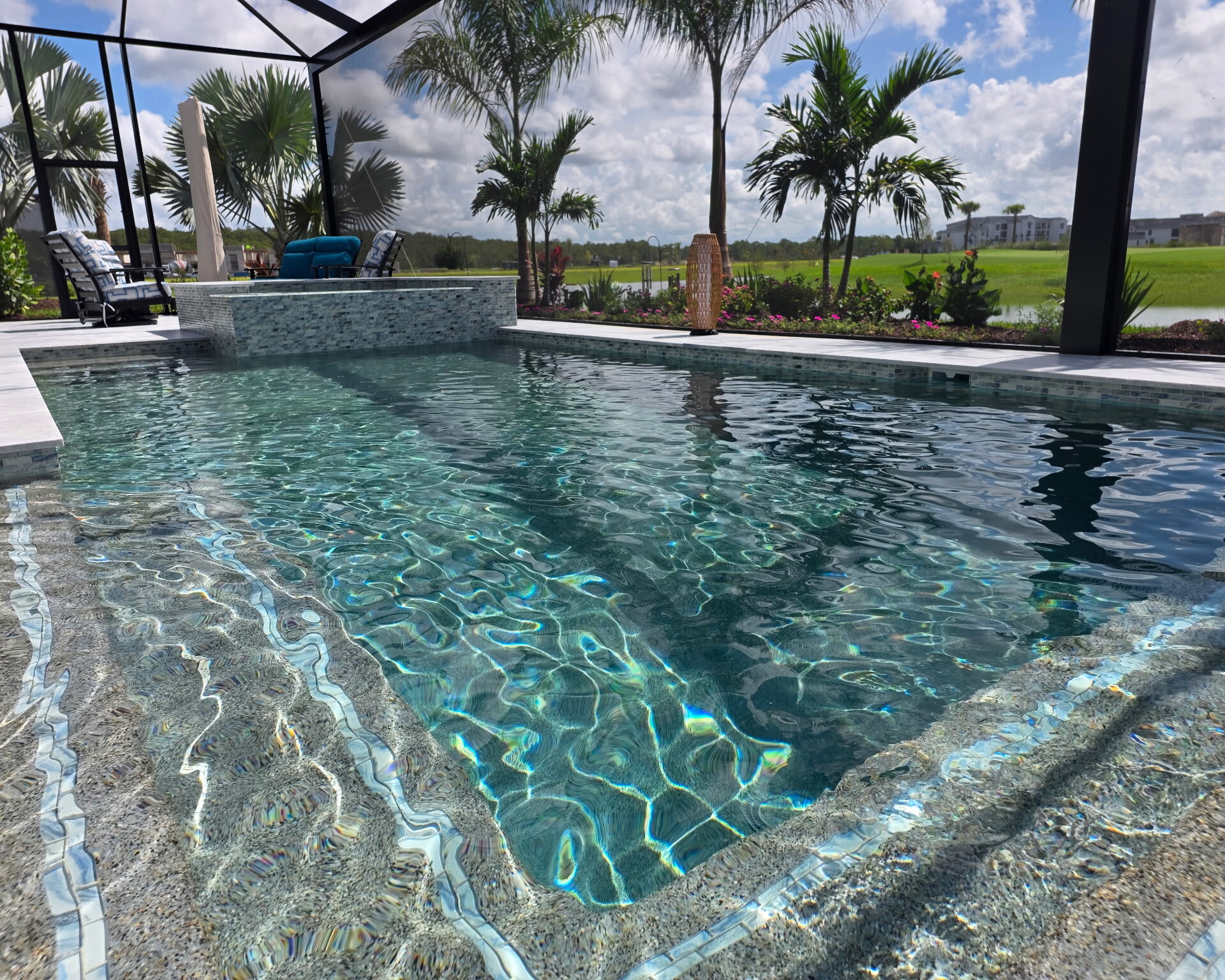 Glass tile step accents in a Caribbean Blue PebbleTec pool in Babcock Ranch